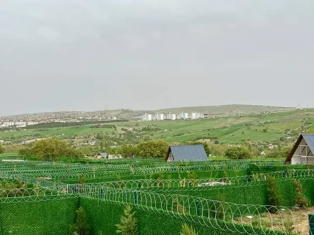 Hobi bahçeleri arasında çim çit kaplı tel örgü ve üstünde spiral jiletli tel