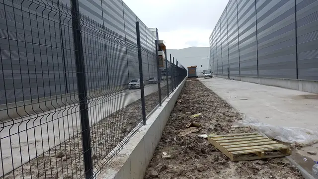 Fabrika önünde beton duvar üstüne kurulmuş antrasit 3D panel çit hattı
